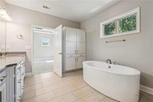 bathroom with vanity, visible vents, a wealth of natural light, and a freestanding bath