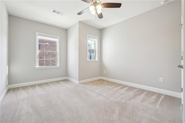 empty room with visible vents, light colored carpet, baseboards, and ceiling fan