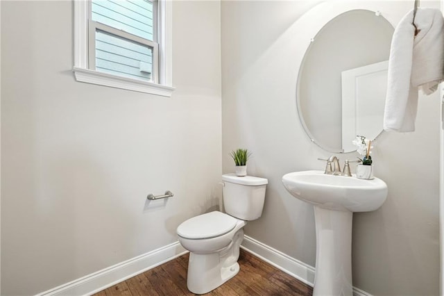 bathroom featuring a sink, toilet, baseboards, and wood finished floors