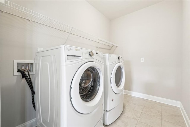 laundry area featuring washer and clothes dryer, laundry area, baseboards, and light tile patterned floors