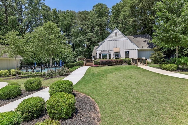 view of front of home featuring board and batten siding, a wooden deck, and a front yard