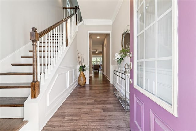 foyer entrance featuring crown molding, stairway, a decorative wall, and wood finished floors