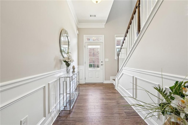 foyer featuring visible vents, stairway, ornamental molding, wainscoting, and wood finished floors