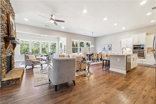 living area with dark wood-style floors, plenty of natural light, recessed lighting, and a fireplace