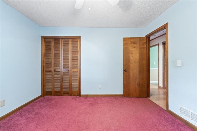 unfurnished bedroom featuring a textured ceiling, light carpet, ceiling fan, and a closet