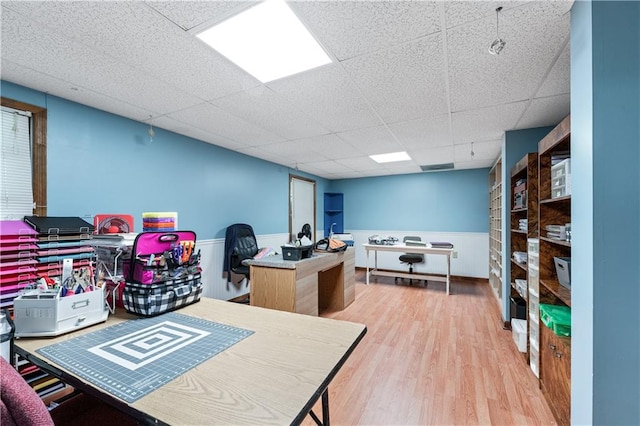 office with wood-type flooring and a paneled ceiling