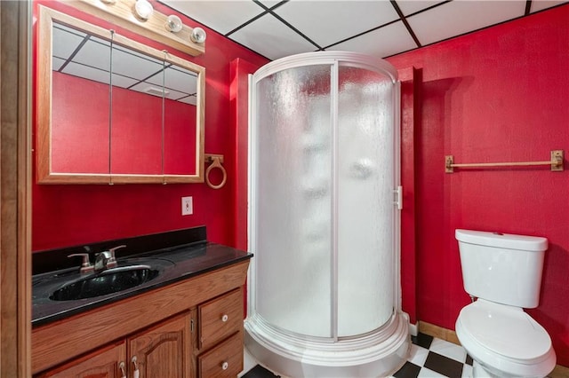 bathroom with a drop ceiling, vanity, a shower with shower door, and toilet