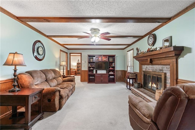 living room with ceiling fan, beamed ceiling, a textured ceiling, carpet floors, and a fireplace