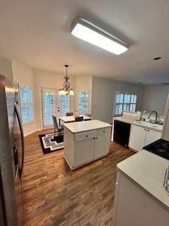 kitchen with decorative light fixtures, stainless steel refrigerator, a chandelier, hardwood / wood-style flooring, and a center island