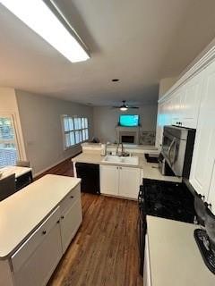 kitchen with ceiling fan, dark hardwood / wood-style flooring, a kitchen island, sink, and white cabinetry