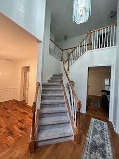 stairs featuring a high ceiling, wood-type flooring, and a chandelier