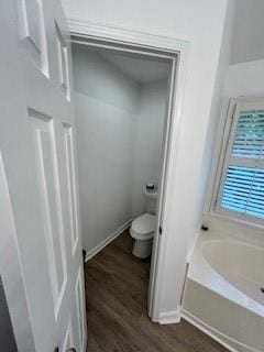 bathroom featuring a bath, hardwood / wood-style flooring, and toilet