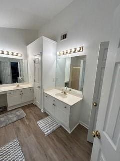 bathroom with vaulted ceiling, dual vanity, and hardwood / wood-style flooring