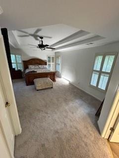 carpeted bedroom featuring a tray ceiling, crown molding, and multiple windows