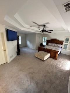 unfurnished bedroom featuring a raised ceiling, ceiling fan, and carpet floors