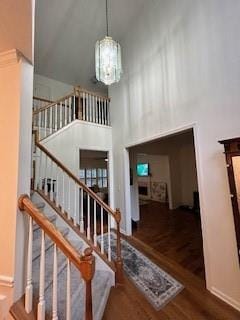 stairway featuring a chandelier, dark hardwood / wood-style floors, and a towering ceiling