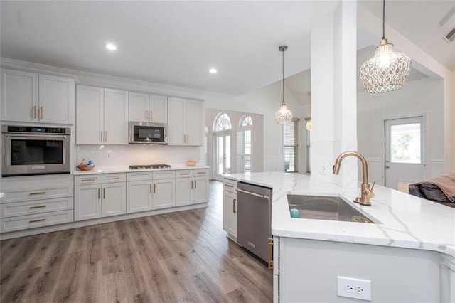 kitchen featuring appliances with stainless steel finishes, backsplash, a sink, and light wood-style flooring