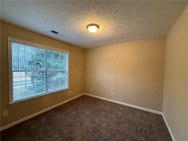 unfurnished room featuring baseboards, visible vents, dark colored carpet, and a textured ceiling