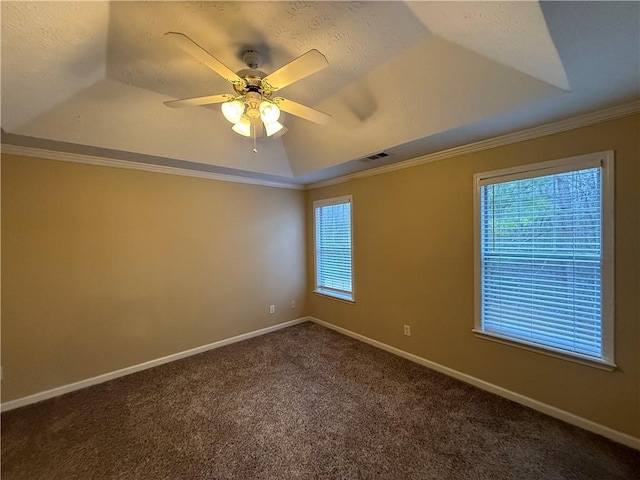 empty room featuring baseboards, visible vents, a raised ceiling, dark colored carpet, and crown molding