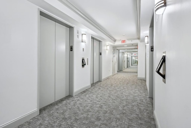 hallway featuring elevator, a raised ceiling, and light carpet