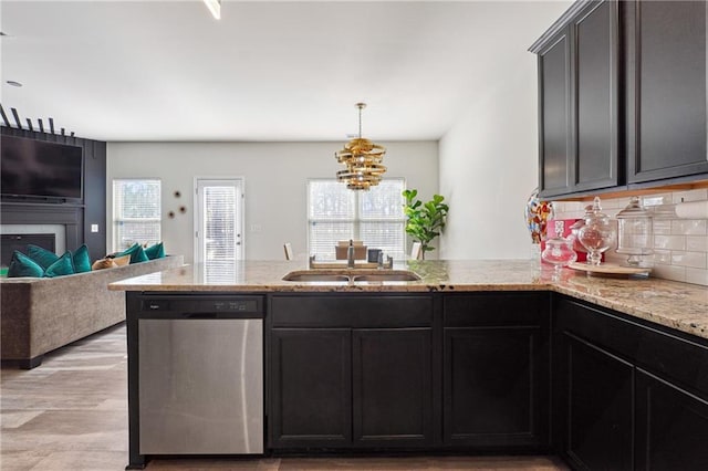 kitchen featuring light stone counters, stainless steel dishwasher, sink, and backsplash