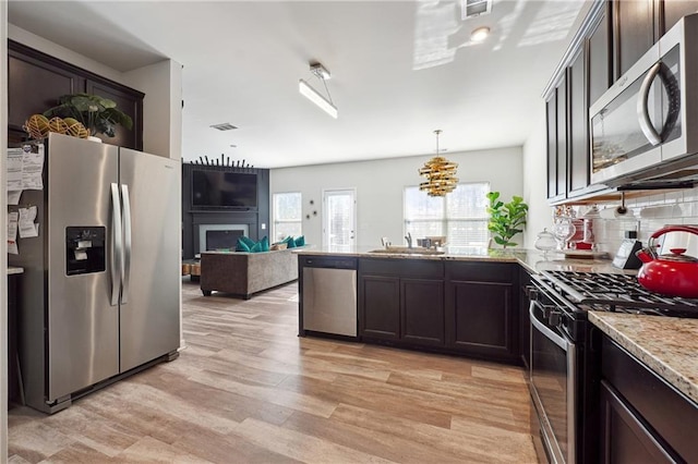 kitchen featuring pendant lighting, dark brown cabinets, stainless steel appliances, and light hardwood / wood-style floors