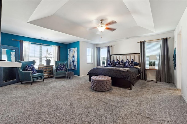 carpeted bedroom featuring ceiling fan and a tray ceiling