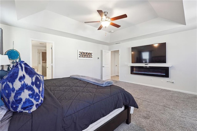 carpeted bedroom with a raised ceiling and ceiling fan