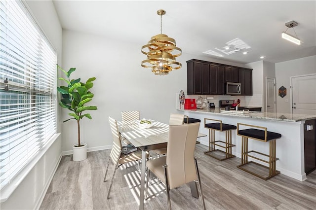 dining area with light hardwood / wood-style flooring and a notable chandelier