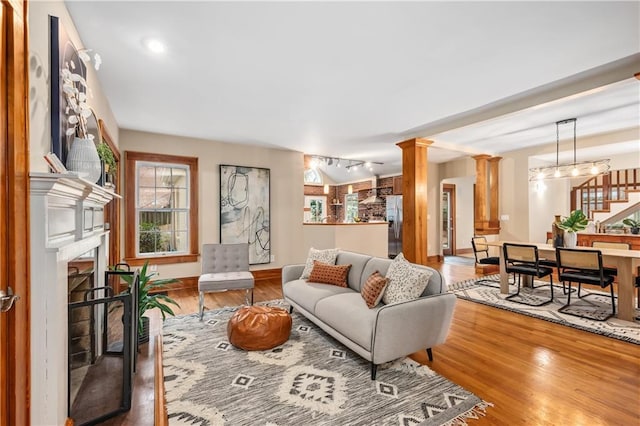 living room featuring hardwood / wood-style flooring, track lighting, and decorative columns