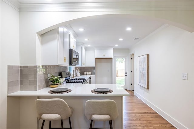139 Sisson Ave NE, Atlanta, GA 30317 - kitchen with stainless steel appliances, arched walkways, light countertops, decorative backsplash, and a peninsula