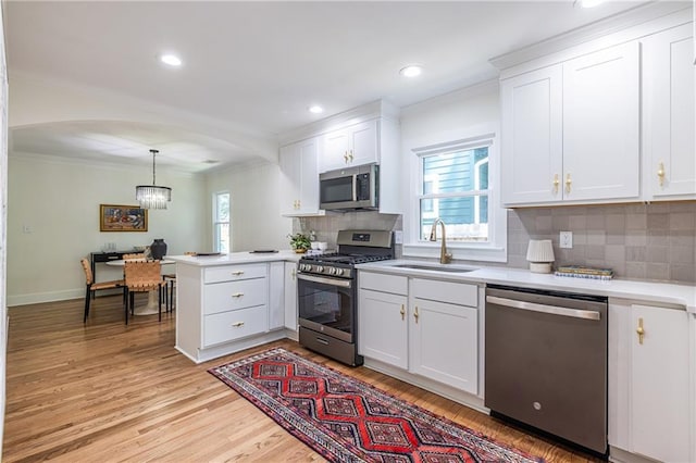 139 Sisson Ave NE, Atlanta, GA 30317 - kitchen featuring appliances with stainless steel finishes, a sink, ornamental molding, a peninsula, and light countertops
