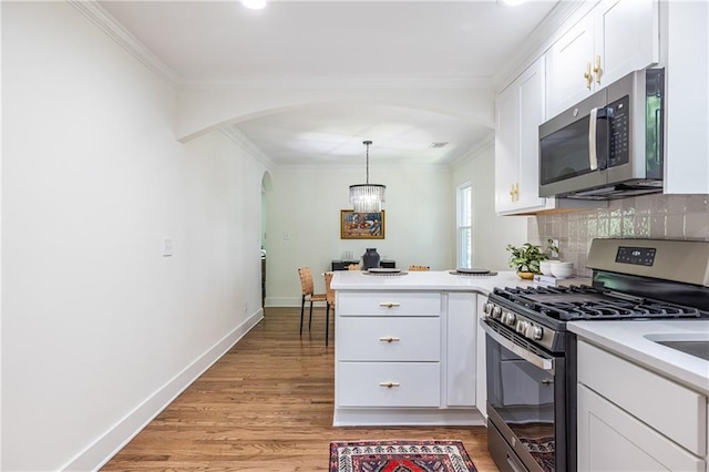 139 Sisson Ave NE, Atlanta, GA 30317 - kitchen featuring stainless steel appliances, a peninsula, ornamental molding, white cabinets, and light wood-type flooring