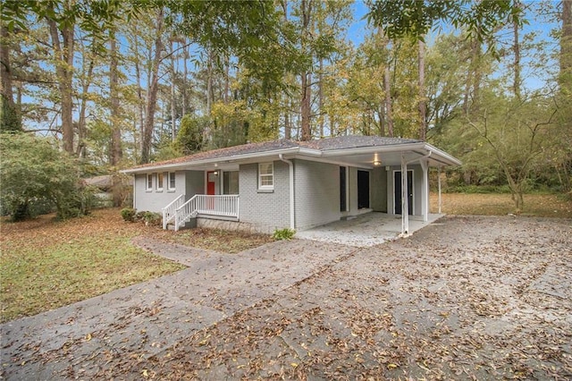 3449 Misty Valley Rd, Decatur, GA 30032 - single story home with driveway, a carport, covered porch, brick siding, and view of wooded area