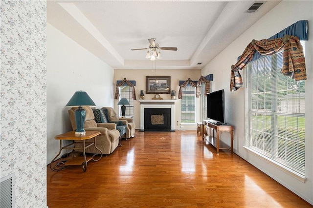 1900 Green Oak Cir, Lawrenceville, GA 30043 - living room with wood finished floors, ceiling fan, a fireplace with flush hearth, and a raised ceiling