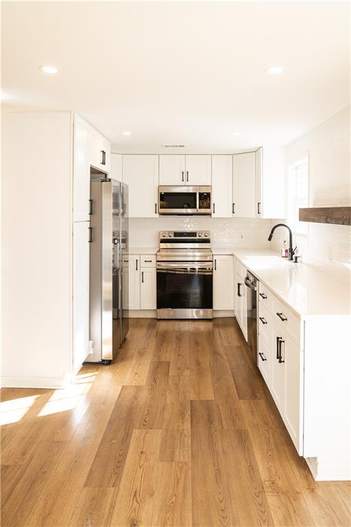 kitchen featuring light hardwood / wood-style floors, stainless steel appliances, and white cabinetry