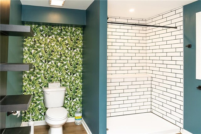 bathroom with tiled shower and wood-type flooring