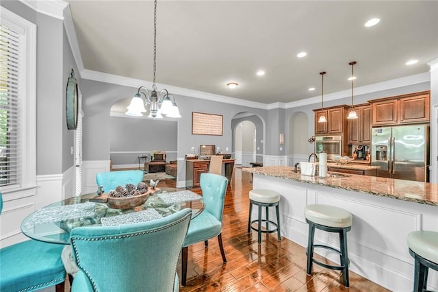271 Learwood Ln, Atlanta, GA 30349 - dining space with arched walkways, a wainscoted wall, ornamental molding, a chandelier, and wood finished floors