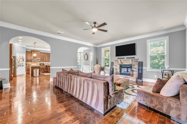 271 Learwood Ln, Atlanta, GA 30349 - living room featuring arched walkways, a fireplace, a ceiling fan, dark wood-style flooring, and ornamental molding