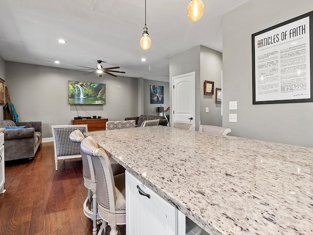 kitchen featuring dark wood-style floors, light stone counters, recessed lighting, hanging light fixtures, and open floor plan