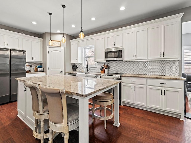 kitchen featuring dark wood-style floors, a kitchen island, appliances with stainless steel finishes, and white cabinets