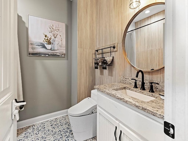 bathroom featuring baseboards, vanity, toilet, and tile patterned floors