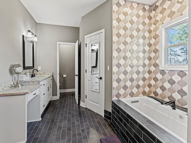 bathroom featuring a garden tub, vanity, baseboards, and wood finished floors