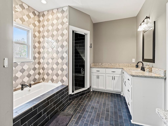 full bathroom featuring a garden tub, vanity, and recessed lighting