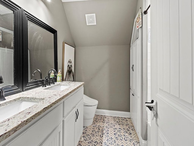 bathroom with double vanity, baseboards, toilet, lofted ceiling, and a sink