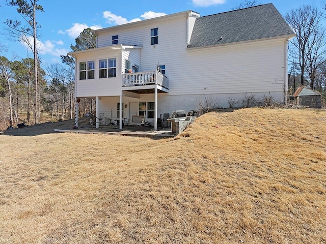 back of property with a patio area, a lawn, a wooden deck, and roof with shingles