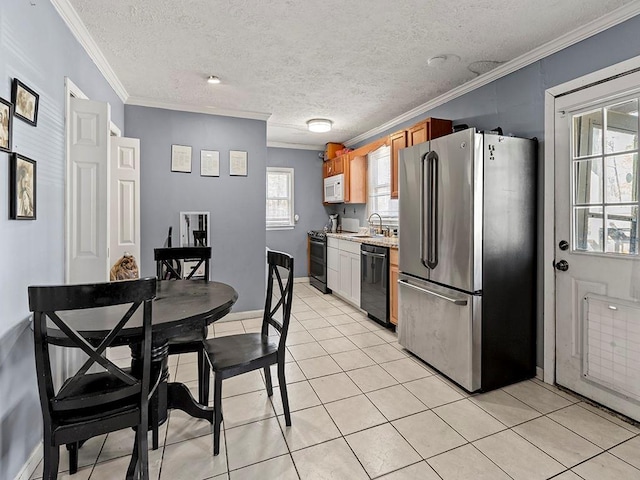 kitchen with light tile patterned floors, ornamental molding, light countertops, black appliances, and a sink