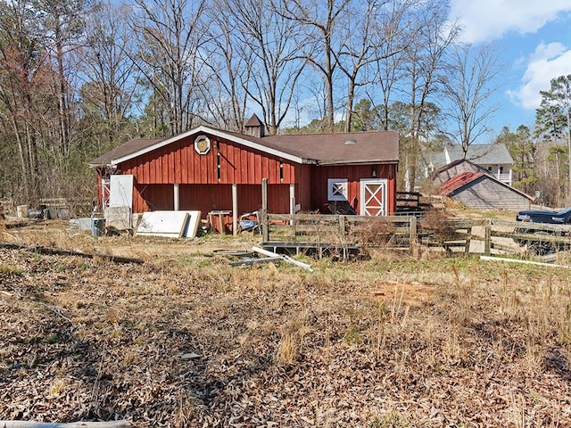 view of front of house with a barn, fence, and an outbuilding