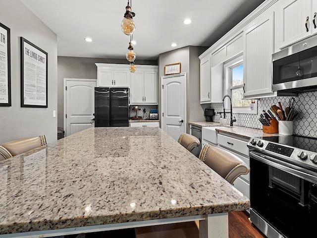 kitchen with stainless steel appliances, a kitchen island, decorative backsplash, and light stone countertops