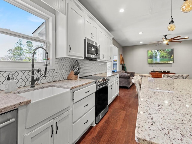 kitchen with dark wood-style floors, tasteful backsplash, appliances with stainless steel finishes, white cabinetry, and a sink